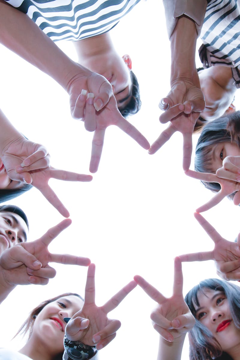A circle of friends forming a star shape with fingers, symbolizing unity and teamwork.